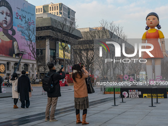 People take photos in front of Young-hee, a robotic doll from Netflix's ''Squid Game,'' at Gwanghwamun Square in Seoul, South Korea, on Dece...