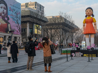 People take photos in front of Young-hee, a robotic doll from Netflix's ''Squid Game,'' at Gwanghwamun Square in Seoul, South Korea, on Dece...