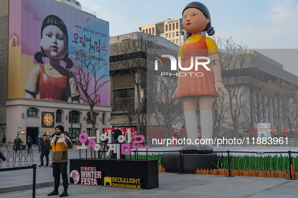 A person takes a photo in front of Young-hee, a robotic doll from Netflix's series ''Squid Game,'' at Gwanghwamun Square in Seoul, South Kor...