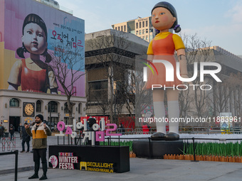 A person takes a photo in front of Young-hee, a robotic doll from Netflix's series ''Squid Game,'' at Gwanghwamun Square in Seoul, South Kor...