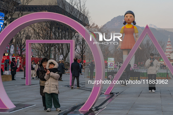 People take photos in front of Young-hee, a robotic doll from Netflix's ''Squid Game,'' at Gwanghwamun Square in Seoul, South Korea, on Dece...