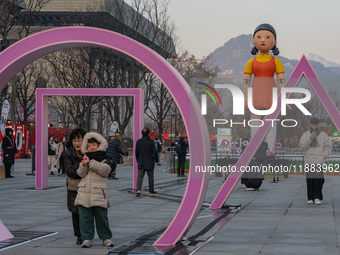 People take photos in front of Young-hee, a robotic doll from Netflix's ''Squid Game,'' at Gwanghwamun Square in Seoul, South Korea, on Dece...