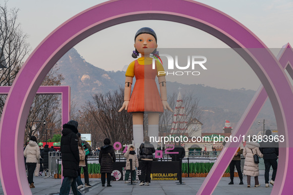 People take photos in front of Young-hee, a robotic doll from Netflix's ''Squid Game,'' at Gwanghwamun Square in Seoul, South Korea, on Dece...