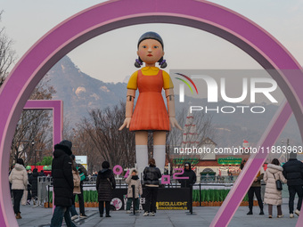 People take photos in front of Young-hee, a robotic doll from Netflix's ''Squid Game,'' at Gwanghwamun Square in Seoul, South Korea, on Dece...