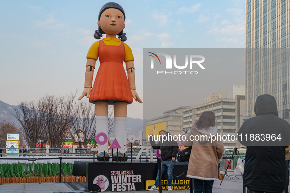 A person takes a photo in front of Young-hee, a robotic doll from Netflix's series ''Squid Game,'' at Gwanghwamun Square in Seoul, South Kor...