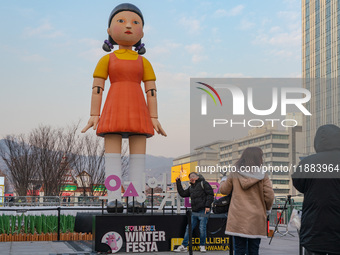 A person takes a photo in front of Young-hee, a robotic doll from Netflix's series ''Squid Game,'' at Gwanghwamun Square in Seoul, South Kor...