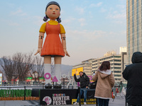 A person takes a photo in front of Young-hee, a robotic doll from Netflix's series ''Squid Game,'' at Gwanghwamun Square in Seoul, South Kor...