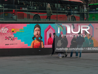 People walk past a displayed billboard for Netflix's ''Squid Game'' new season in Seoul, South Korea, on December 20, 2024. ''Squid Game'' s...