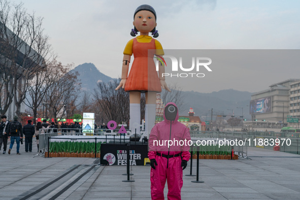 A person dressed as a ''Squid Game'' game guard stands in front of Young-hee, a robotic doll from Netflix's ''Squid Game,'' at Gwanghwamun S...