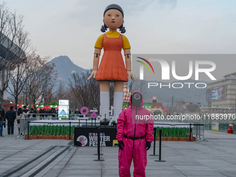 A person dressed as a ''Squid Game'' game guard stands in front of Young-hee, a robotic doll from Netflix's ''Squid Game,'' at Gwanghwamun S...