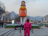 A person dressed as a ''Squid Game'' game guard stands in front of Young-hee, a robotic doll from Netflix's ''Squid Game,'' at Gwanghwamun S...