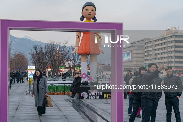 People take photos in front of Young-hee, a robotic doll from Netflix's ''Squid Game,'' at Gwanghwamun Square in Seoul, South Korea, on Dece...