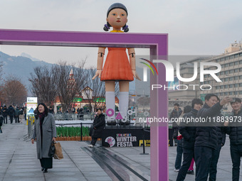 People take photos in front of Young-hee, a robotic doll from Netflix's ''Squid Game,'' at Gwanghwamun Square in Seoul, South Korea, on Dece...