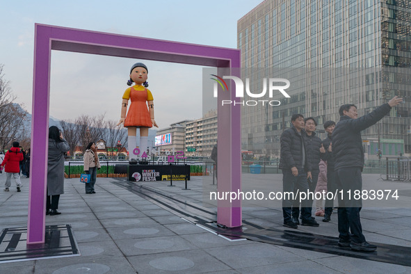 People take photos in front of Young-hee, a robotic doll from Netflix's ''Squid Game,'' at Gwanghwamun Square in Seoul, South Korea, on Dece...