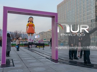 People take photos in front of Young-hee, a robotic doll from Netflix's ''Squid Game,'' at Gwanghwamun Square in Seoul, South Korea, on Dece...