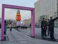 People take photos in front of Young-hee, a robotic doll from Netflix's ''Squid Game,'' at Gwanghwamun Square in Seoul, South Korea, on Dece...