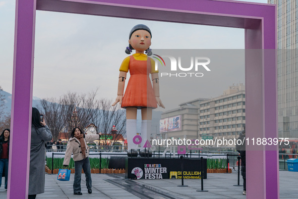 A person takes a photo in front of Young-hee, a robotic doll from Netflix's series ''Squid Game,'' at Gwanghwamun Square in Seoul, South Kor...