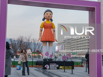 A person takes a photo in front of Young-hee, a robotic doll from Netflix's series ''Squid Game,'' at Gwanghwamun Square in Seoul, South Kor...