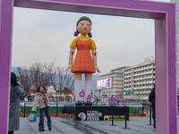 A person takes a photo in front of Young-hee, a robotic doll from Netflix's series ''Squid Game,'' at Gwanghwamun Square in Seoul, South Kor...