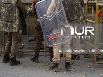 Assam police personnel stand guard during an Indian Youth Congress protest against the state government over the death of a party worker in...