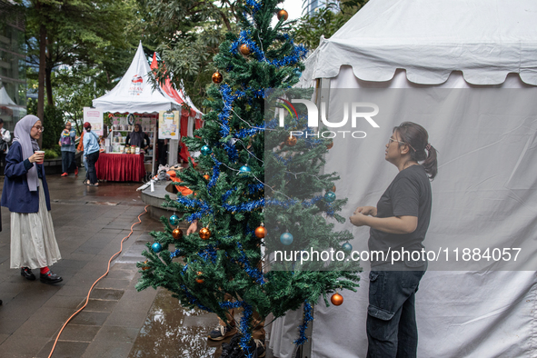 A woman arranges a Christmas tree near the MRT Station in Jakarta, Indonesia, on December 20, 2024. The world's most populous Muslim country...