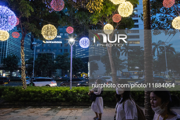 People walk on an illuminated street in Jakarta, Indonesia, on December 20, 2024. The world's most populous Muslim country prepares for Chri...