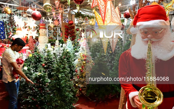 A customer with his child checks decorative Christmas trees ahead of the Christmas festival at a shop in Hyderabad, India, on December 20, 2...