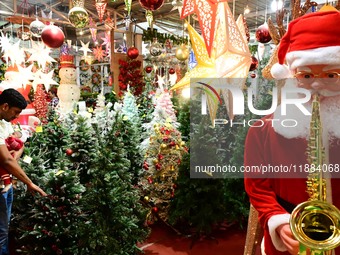 A customer with his child checks decorative Christmas trees ahead of the Christmas festival at a shop in Hyderabad, India, on December 20, 2...