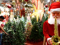 A customer with his child checks decorative Christmas trees ahead of the Christmas festival at a shop in Hyderabad, India, on December 20, 2...