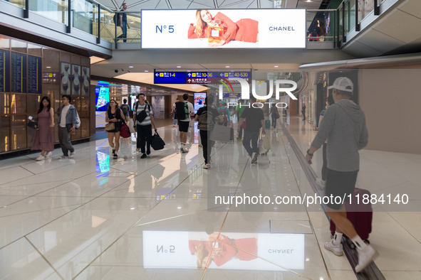 Passengers walk in the Hong Kong International Airport in Hong Kong, China, on November 3, 2024, as a publicity for the N? 5 of Chanel refle...