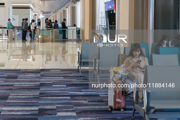 A traveler waits for her plane at Hong Kong International Airport in Hong Kong, China, on December 1, 2024, as other travelers board a plane...