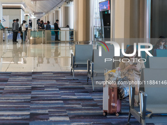 A traveler waits for her plane at Hong Kong International Airport in Hong Kong, China, on December 1, 2024, as other travelers board a plane...