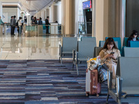 A traveler waits for her plane at Hong Kong International Airport in Hong Kong, China, on December 1, 2024, as other travelers board a plane...