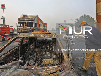 Firefighters douse the fire at the site of the accident after a tanker loaded with LPG collides with other vehicles and catches fire on the...