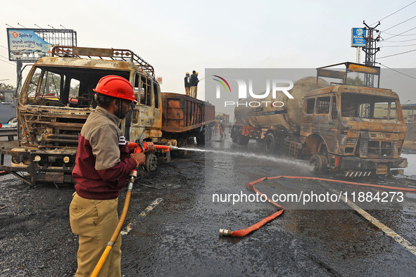 Firefighters douse the fire at the site of the accident after a tanker loaded with LPG collides with other vehicles and catches fire on the...