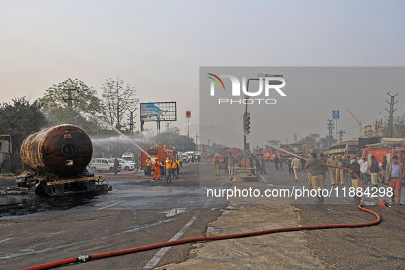 Firefighters douse the fire at the site of the accident after a tanker loaded with LPG collides with other vehicles and catches fire on the...