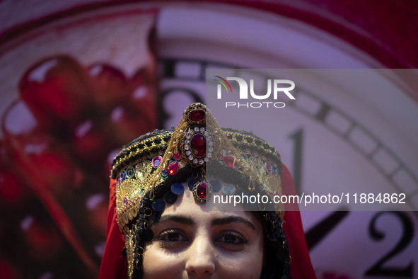 A young Iranian woman wearing a traditional hat poses for a photograph after performing in Yalda Night celebrations at the Iran Mall shoppin...