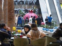 Iranian families stand next to a model of a pomegranate while visiting the Iran Mall shopping mall in northwestern Tehran, Iran, on December...