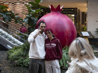 Iranian youths stand together as they pose for a photograph with a model of a pomegranate during Yalda Night celebrations at the Iran Mall s...