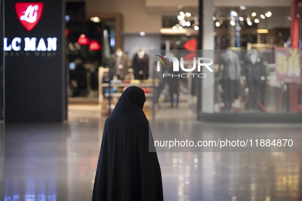 A veiled Iranian woman stands at the Iran Mall shopping mall in northwestern Tehran, Iran, on December 20, 2024, during Yalda Night celebrat...