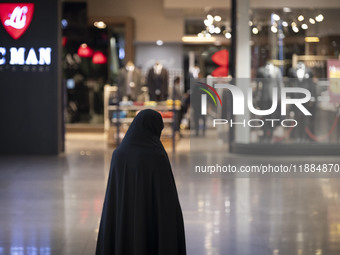 A veiled Iranian woman stands at the Iran Mall shopping mall in northwestern Tehran, Iran, on December 20, 2024, during Yalda Night celebrat...