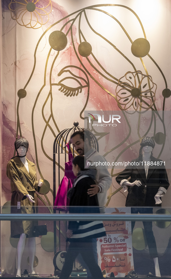 An Iranian couple walks past mannequins decorated in a shop window during Yalda Night celebrations at the Iran Mall shopping mall in northwe...