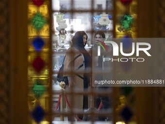 Two Iranian women stand at a handicraft shop while visiting the Iran Mall shopping mall in northwestern Tehran, Iran, on December 20, 2024,...