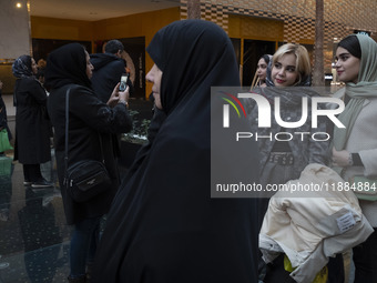 A veiled Iranian woman stands next to two young women while visiting the Iran Mall shopping mall in northwestern Tehran, Iran, on December 2...