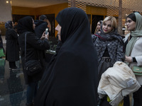 A veiled Iranian woman stands next to two young women while visiting the Iran Mall shopping mall in northwestern Tehran, Iran, on December 2...