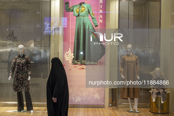 A veiled woman walks past mannequins decorated at a shop window during Yalda Night celebrations at the Iran Mall shopping mall in northweste...