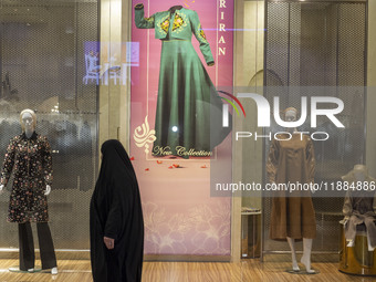 A veiled woman walks past mannequins decorated at a shop window during Yalda Night celebrations at the Iran Mall shopping mall in northweste...