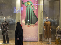 A veiled woman walks past mannequins decorated at a shop window during Yalda Night celebrations at the Iran Mall shopping mall in northweste...