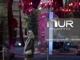 An Iranian woman walks past Yalda Night decorations at the Iran Mall shopping mall in northwestern Tehran, Iran, on December 20, 2024, durin...