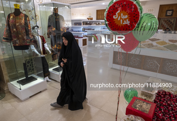 A veiled Iranian woman walks past Yalda Night decorations while visiting the Iran Mall shopping mall in northwestern Tehran, Iran, on Decemb...